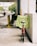 A red bicycle is parked against a white concrete wall, with a neon-green safety vest draped over the seat. The vest has the word 'SECURITY' printed in red capital letters. In the background, there's an outdoor parking area with yellow barriers and some trees visible further back.