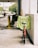 A red bicycle is parked against a white concrete wall, with a neon-green safety vest draped over the seat. The vest has the word 'SECURITY' printed in red capital letters. In the background, there's an outdoor parking area with yellow barriers and some trees visible further back.