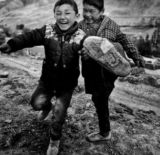 two young boys running down a dirt road