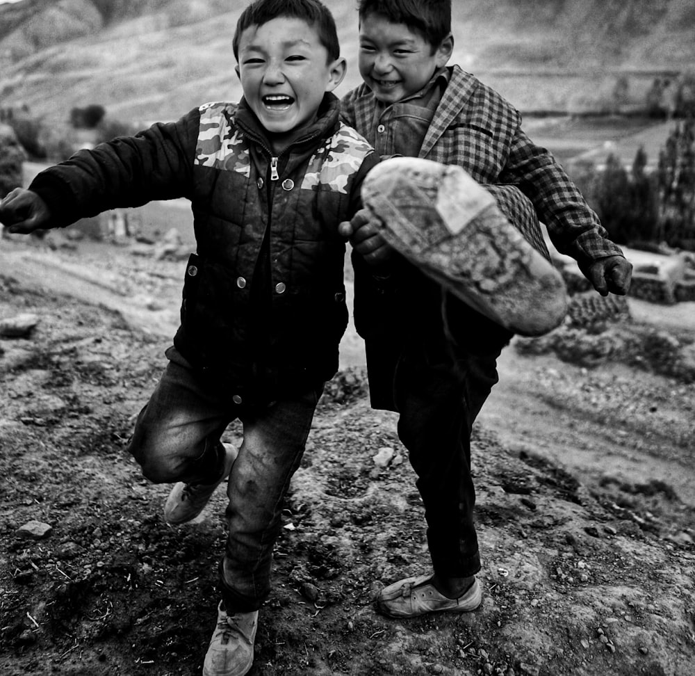 two young boys running down a dirt road