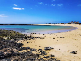 a sandy beach next to a body of water