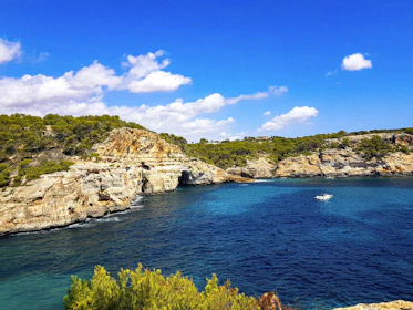 A scenic coastal boat tour with cliffs and clear blue water under a bright sky.