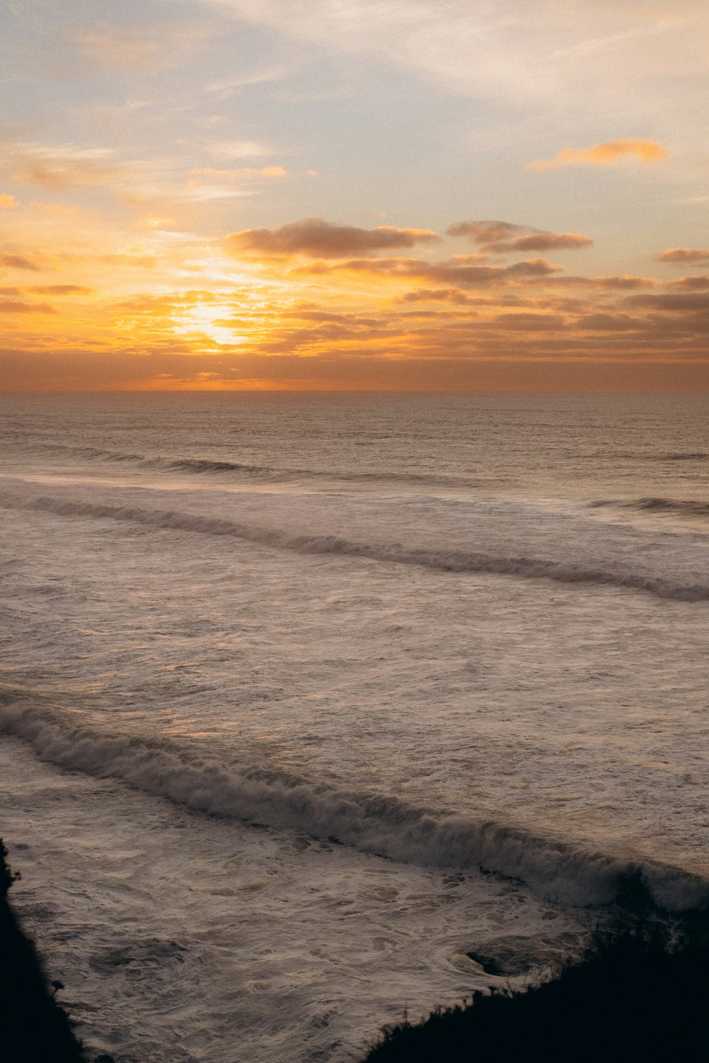 the sun is setting over the ocean with waves