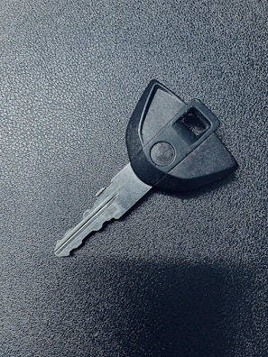 A locksmith expertly cutting a new car key on a portable machine inside a van.