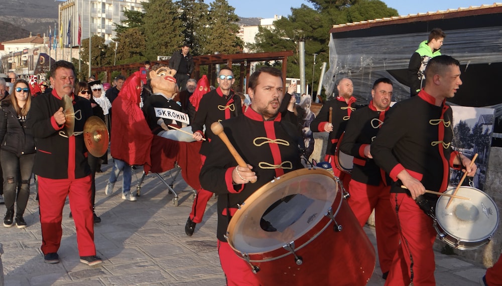 a group of men in red and black outfits marching down a street