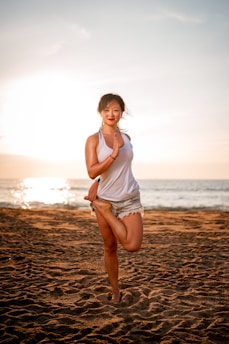 Sunrise yoga session on a sandy beach with turquoise sea in the background.