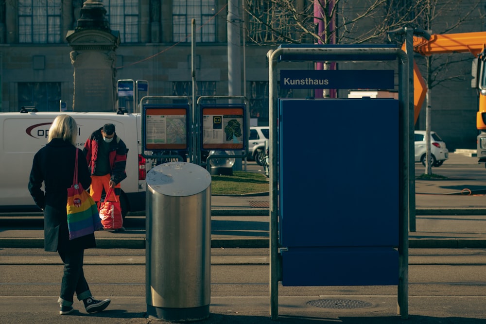 a woman walking down a street next to a bus stop