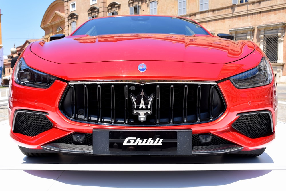 a red masera is parked in front of a building