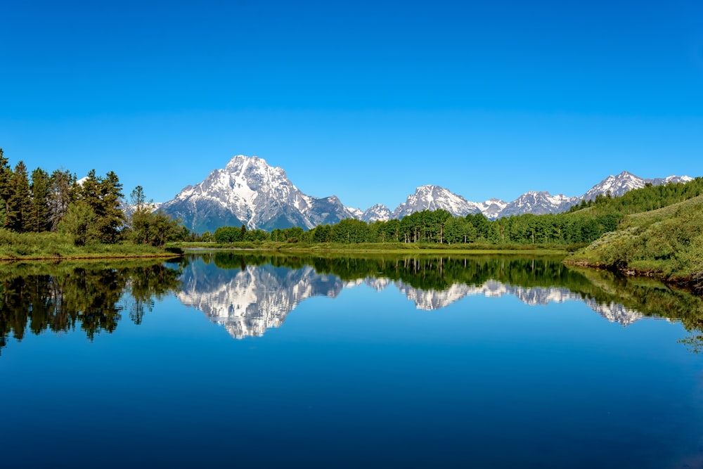 a mountain range is reflected in the still water of a lake