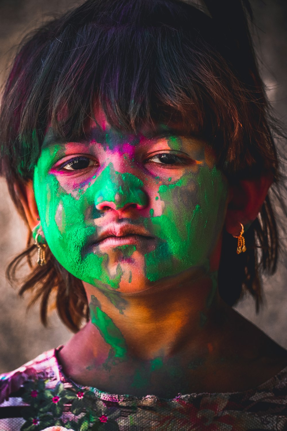 Una ragazza con vernice verde e rosa sul suo viso