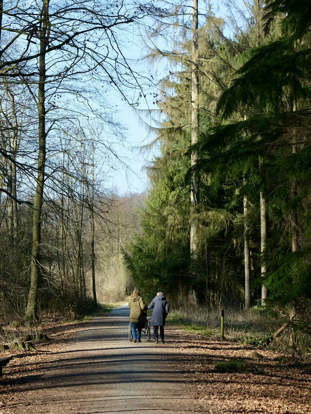 a couple of people walking down a dirt road