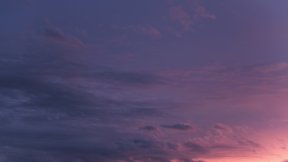 a plane flying in the sky at sunset