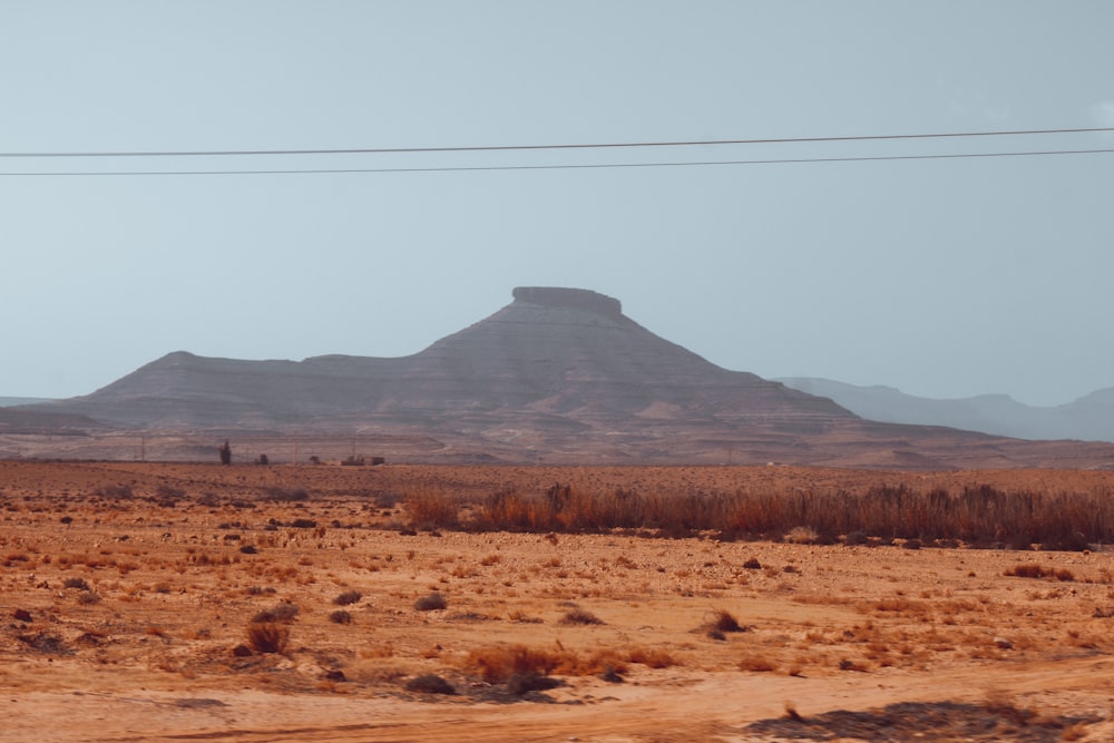 a desert landscape with a mountain in the background