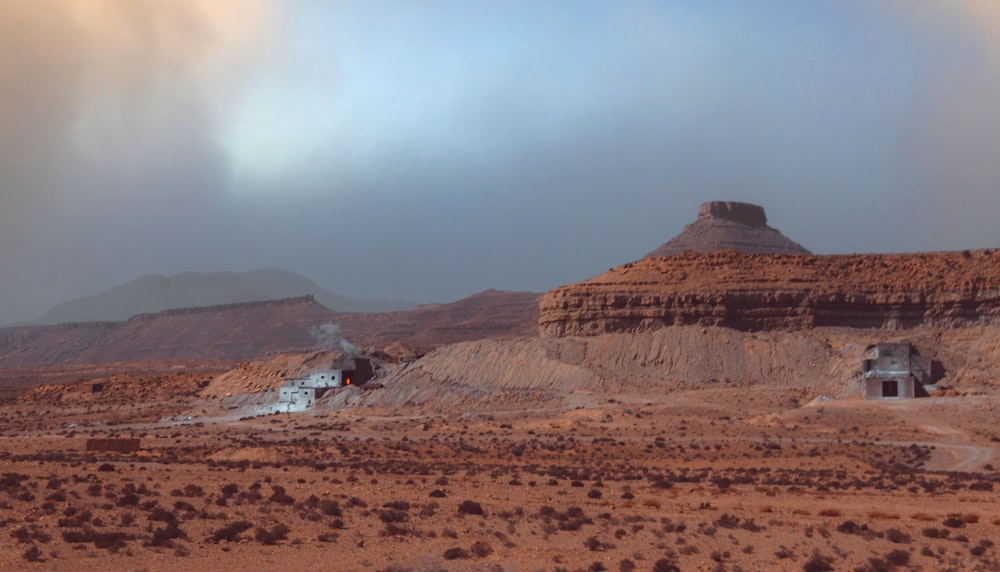 a desert landscape with a few buildings in the distance