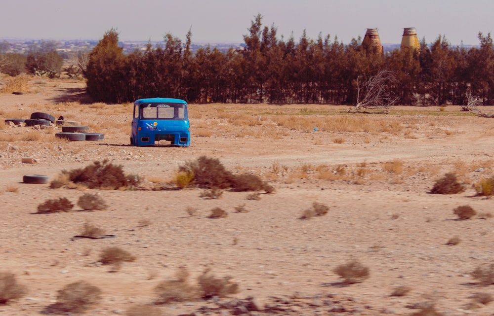 a blue bus parked in the middle of a desert