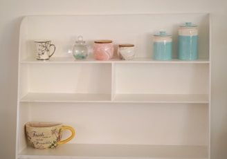a shelf with a cup and mugs on it