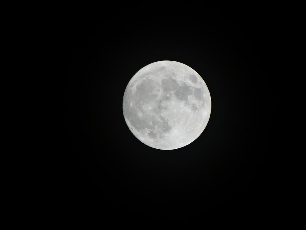 a full moon is seen in the dark sky