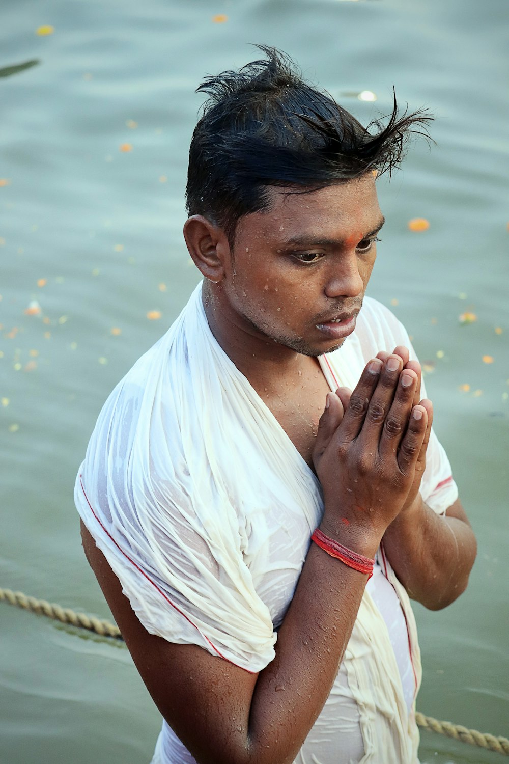 a man standing in the water holding his hands together