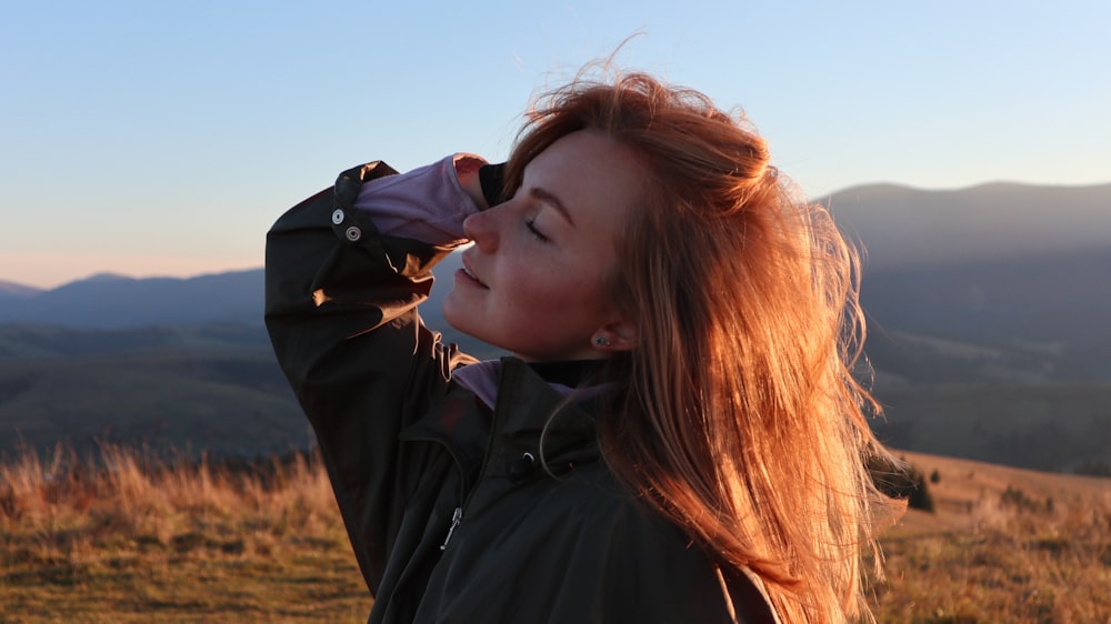 a woman standing on top of a grass covered hillside