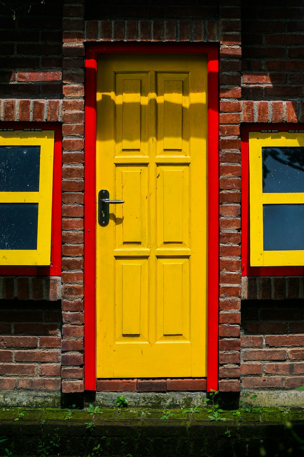 a red and yellow door and windows on a brick building