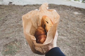 a person holding a paper bag with some food in it