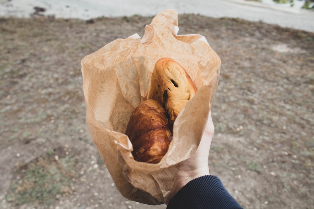 una persona sosteniendo una bolsa de papel con algo de comida en ella