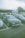 A group of cars parked in a lot with people walking around, likely at a car meet or event. The foreground features a dark-colored Volkswagen with a license plate N529 AWP. Several other cars are parked nearby with a building in the background and trees surrounding the area.