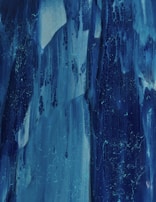 Abstract fluid patterns forming delicate, lace-like structures in muted blues and blacks.