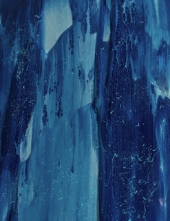 Abstract fluid patterns forming delicate, lace-like structures in muted blues and blacks.