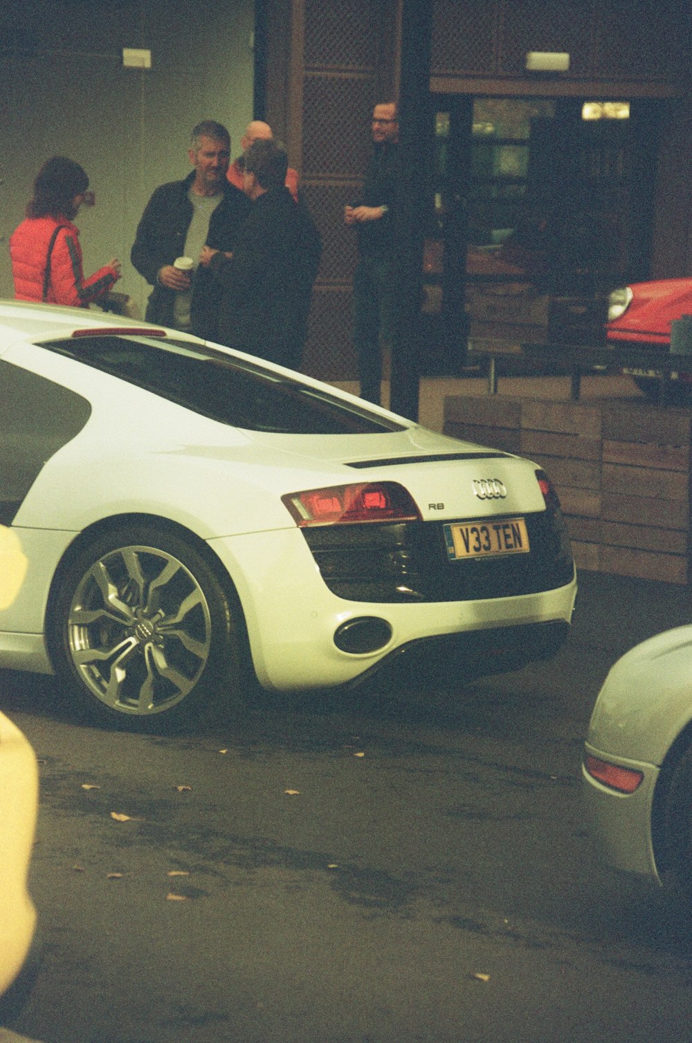 a group of people standing around a white car