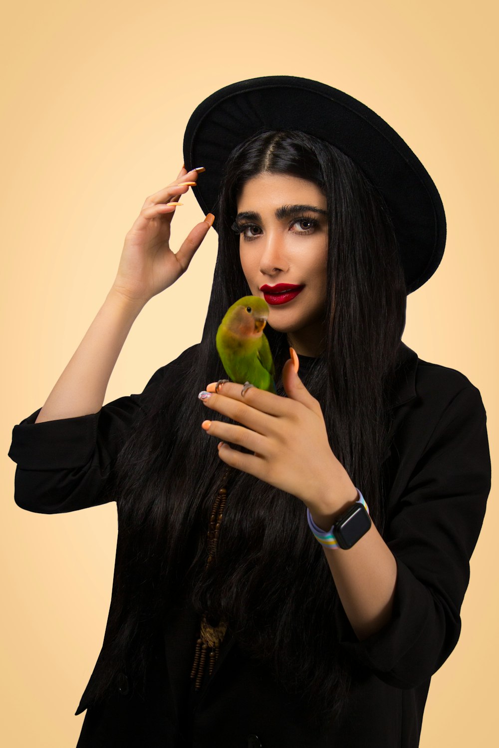 a woman in a black hat holding a green bird
