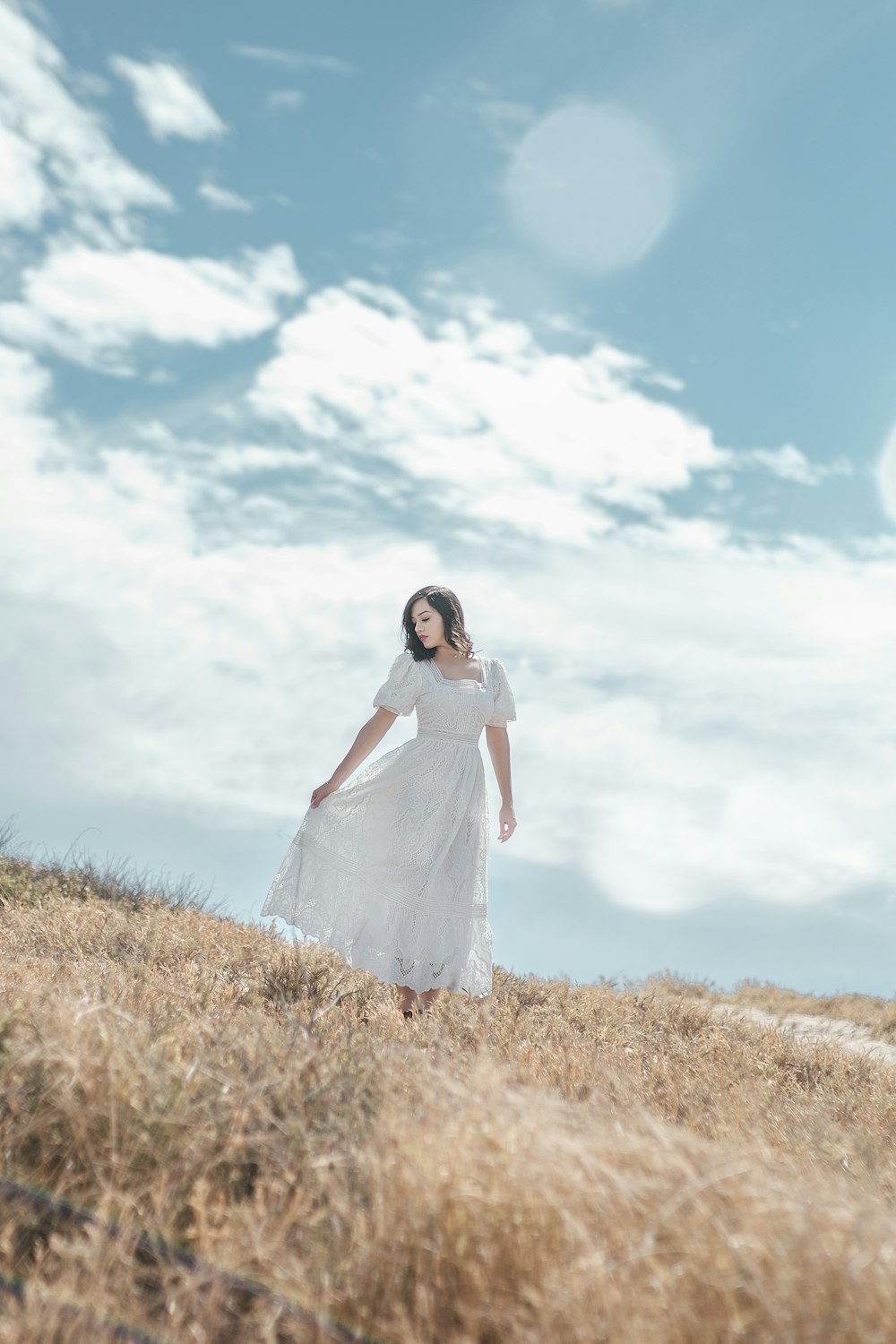 a woman in a white dress standing in a field