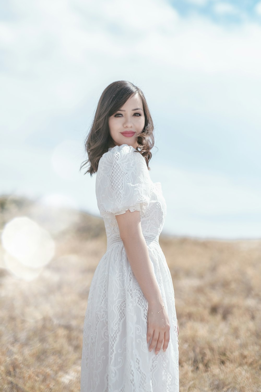 a woman in a white dress standing in a field