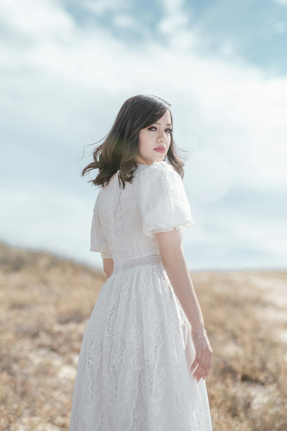 a woman in a white dress standing in a field