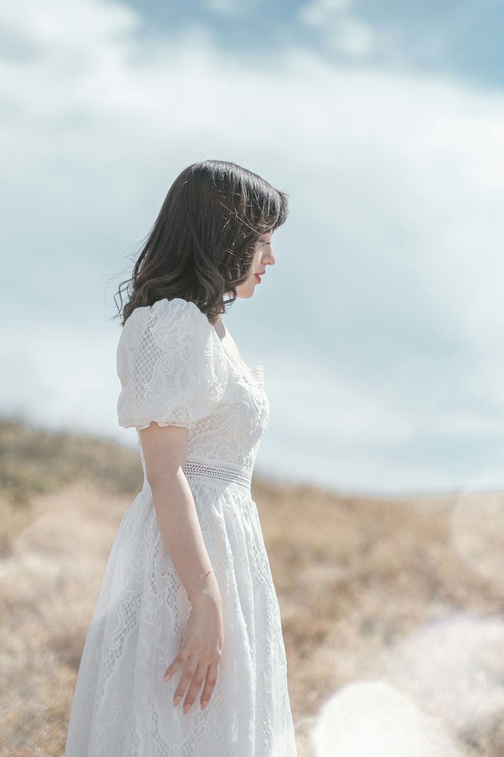 a woman in a white dress standing in a field