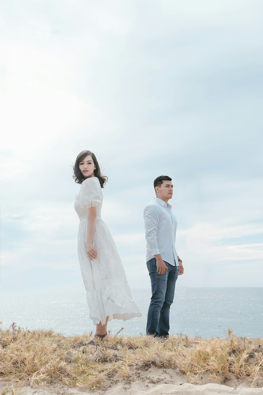 a man and a woman standing on top of a beach