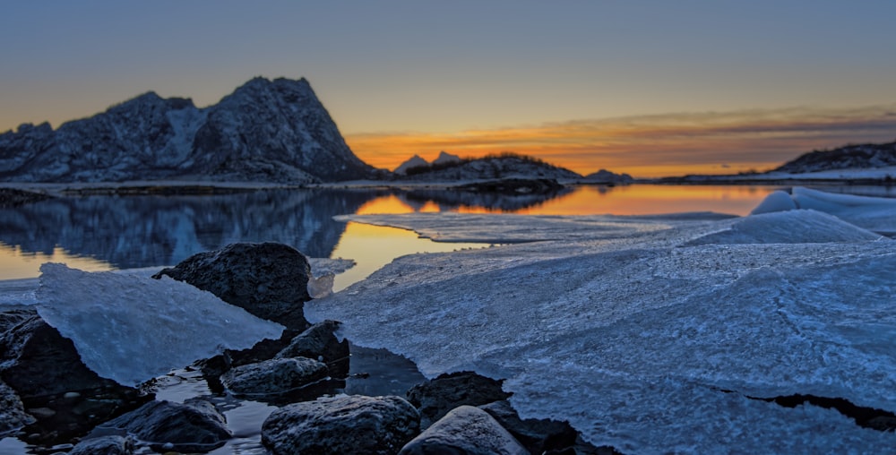 the sun is setting over a mountain lake