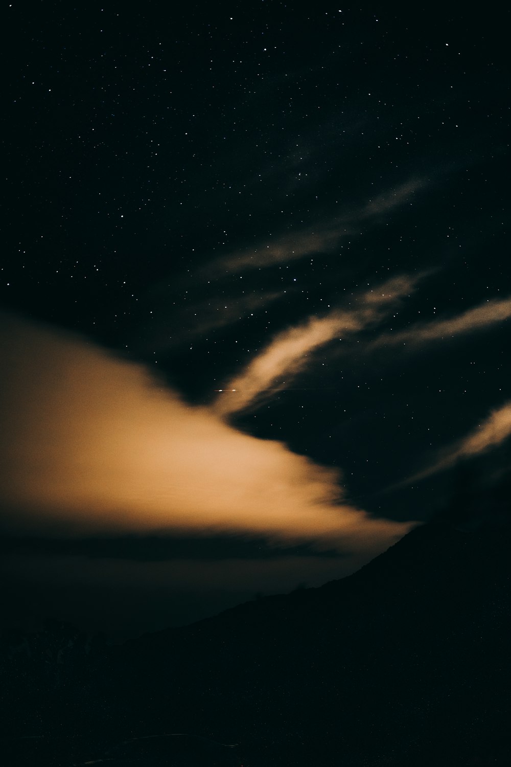 a night sky with a few clouds and stars