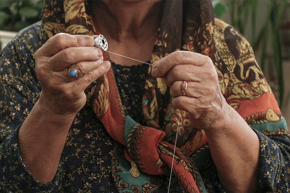 an older woman is knitting a piece of cloth