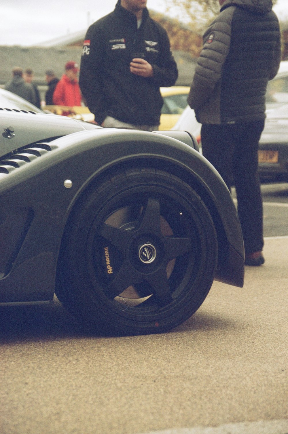 a man standing next to a black sports car