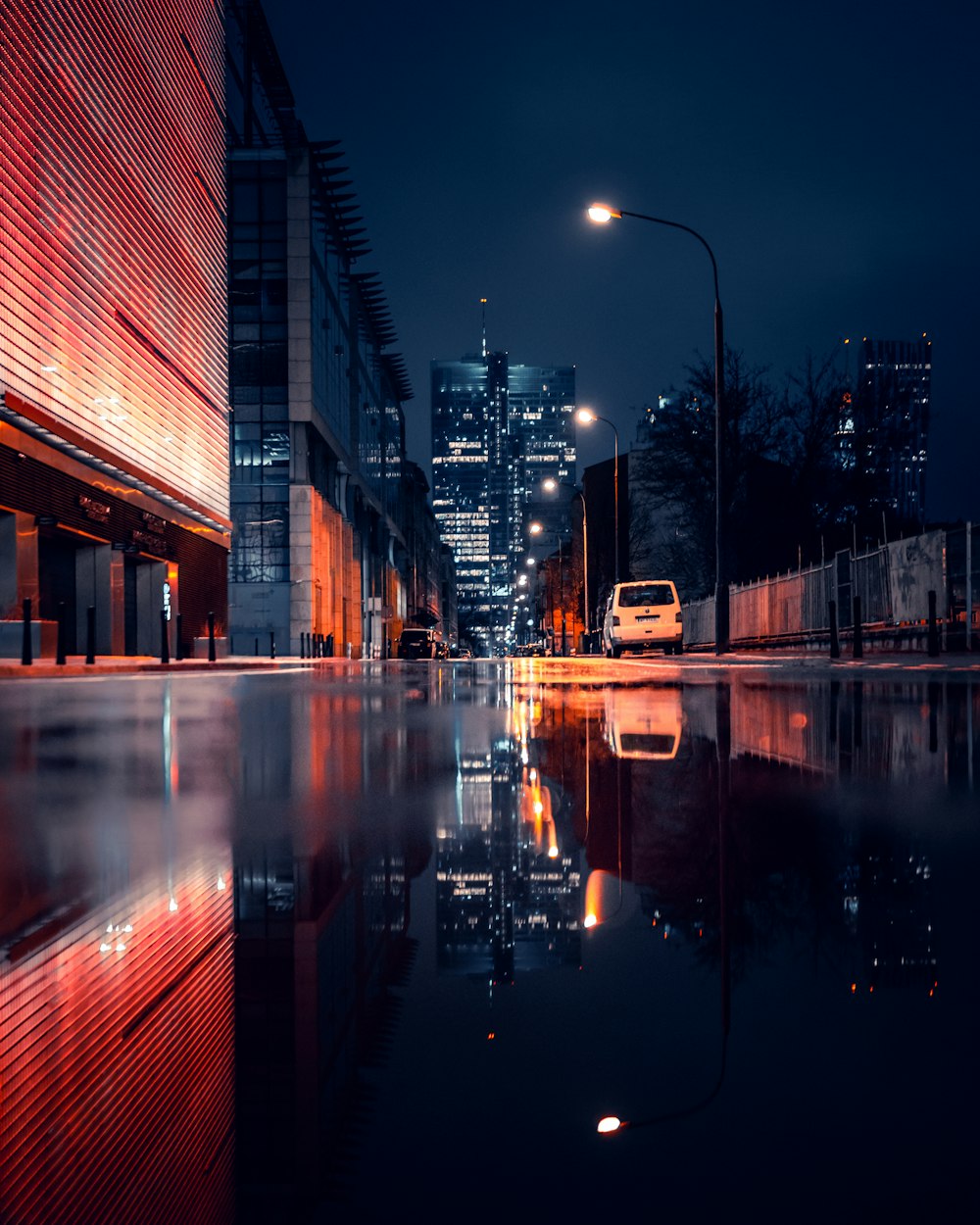 a city street at night with a reflection in the water