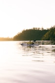 A kayaker paddling calmly on a serene lake during golden hour with reflections on the water