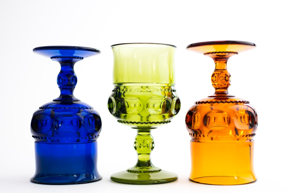 three different colored glass vases sitting next to each other
