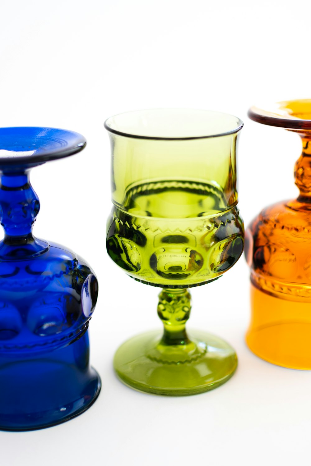 three different colored glass vases sitting next to each other