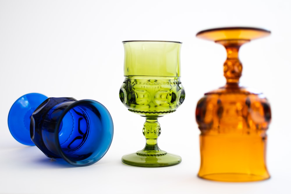 three different colored glass vases sitting next to each other