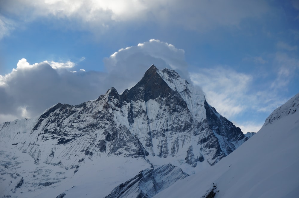 a snow covered mountain under a cloudy blue sky