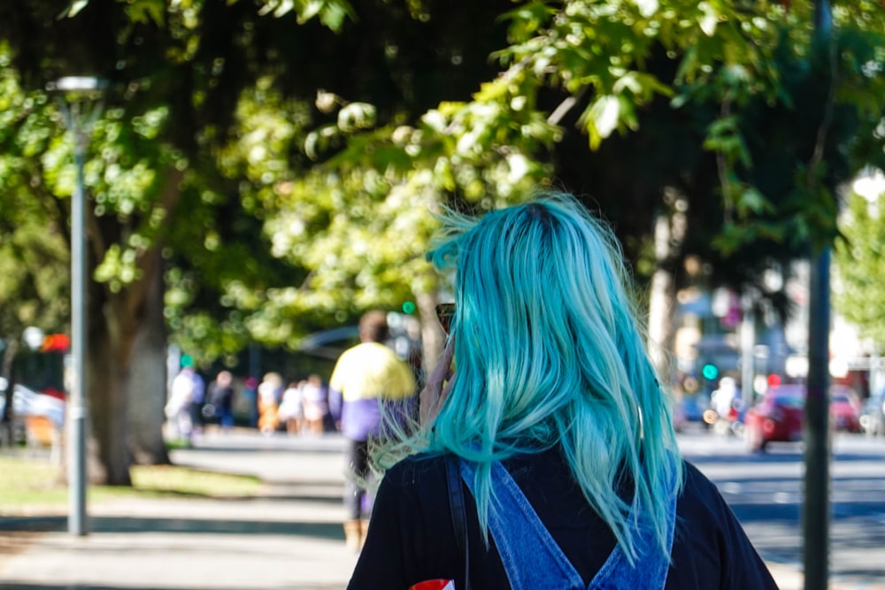 a woman with blue hair is walking down the street