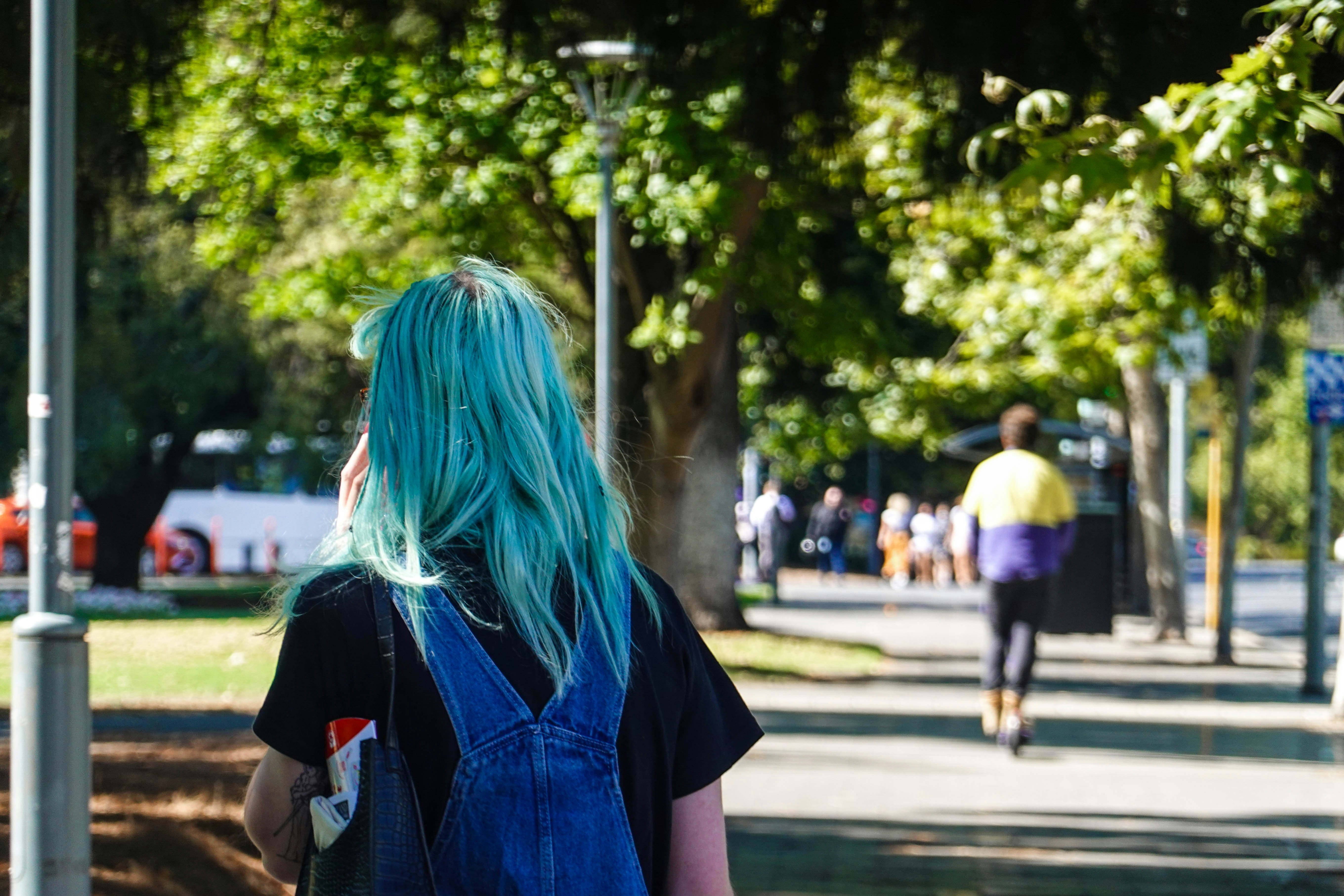 a woman with blue hair walking down a sidewalk