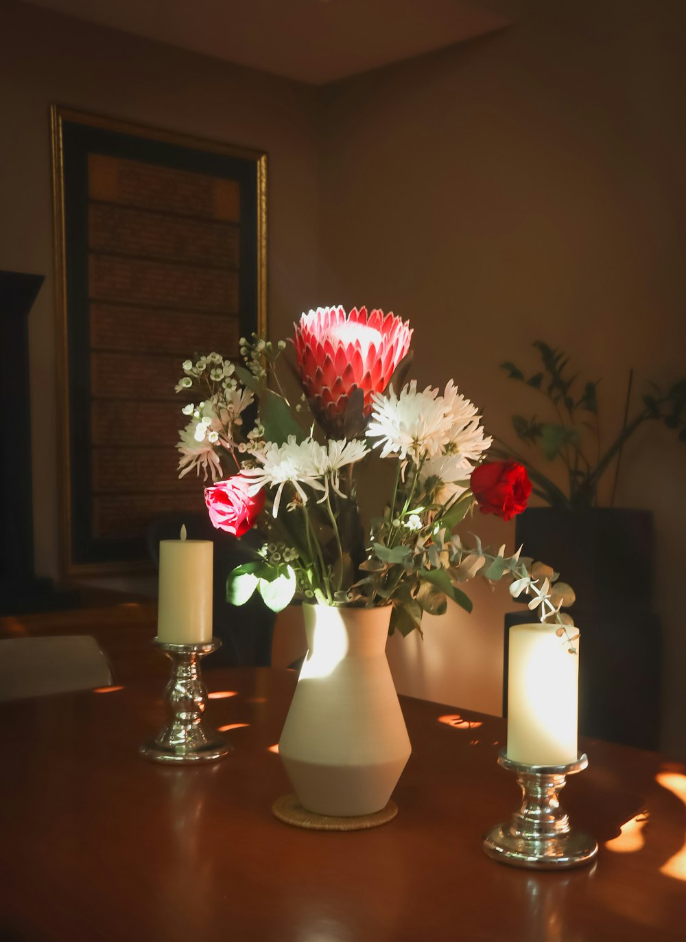 a vase with flowers and candles on a table