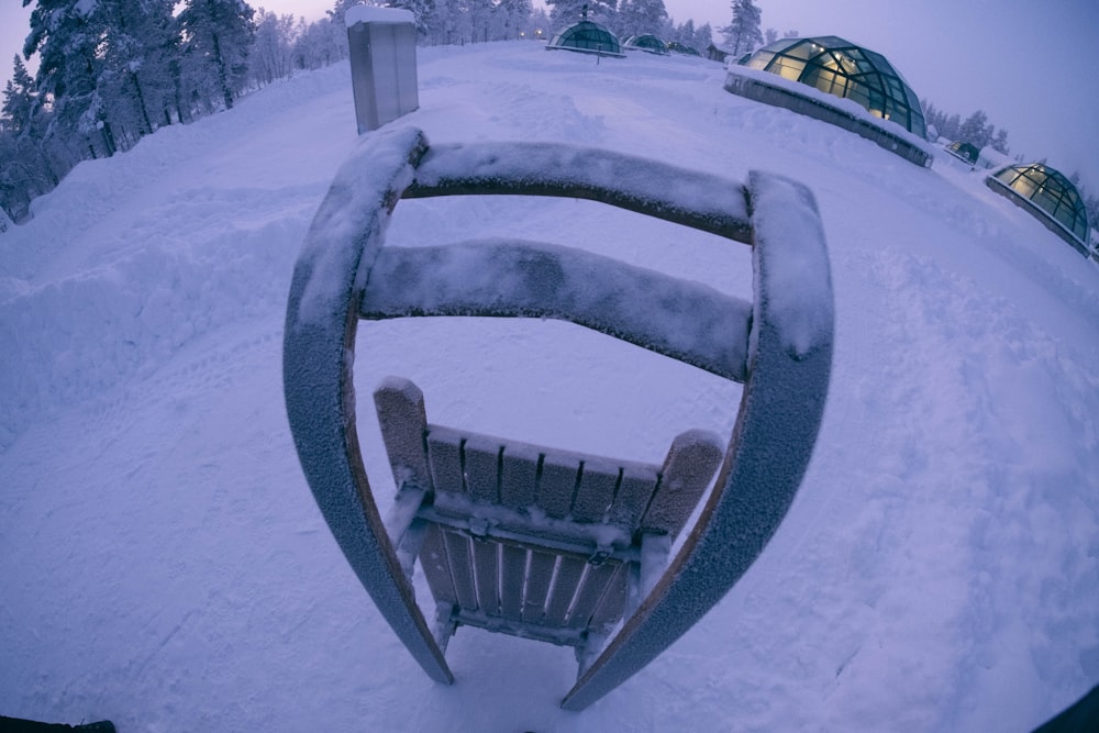 una panchina di legno coperta di neve accanto a una foresta